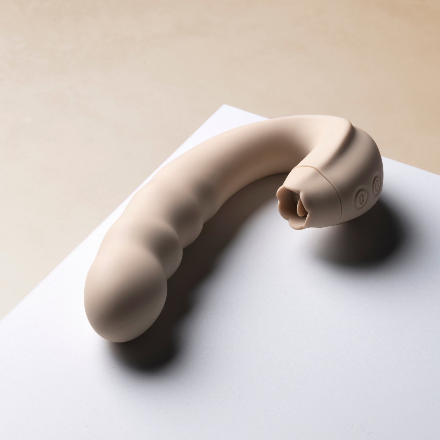 Licking vibrator on a white surface with a beige background