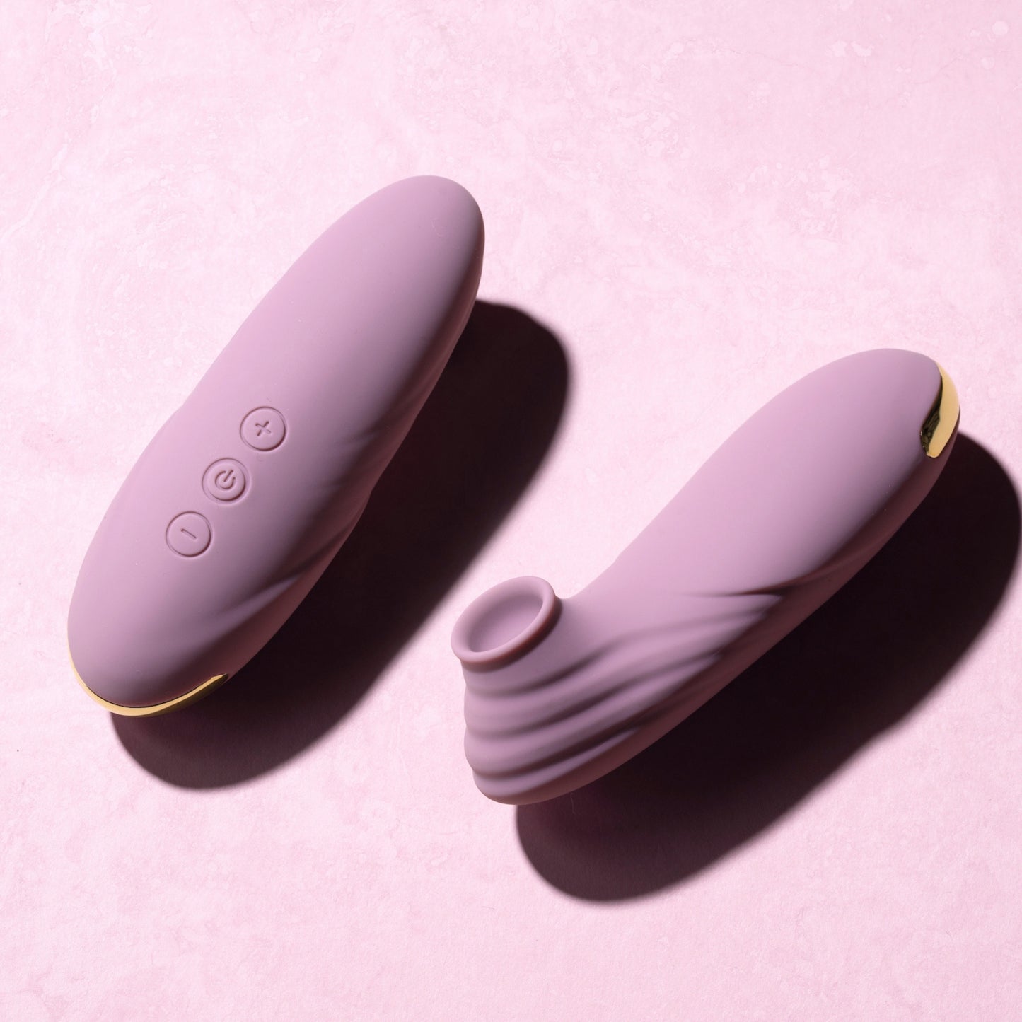 Pink clitoral suction vibrators with control buttons on a pink background
