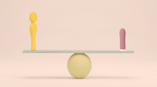 Yellow wand vibrator and pink bullet vibrator balanced on a wooden board with pastel background