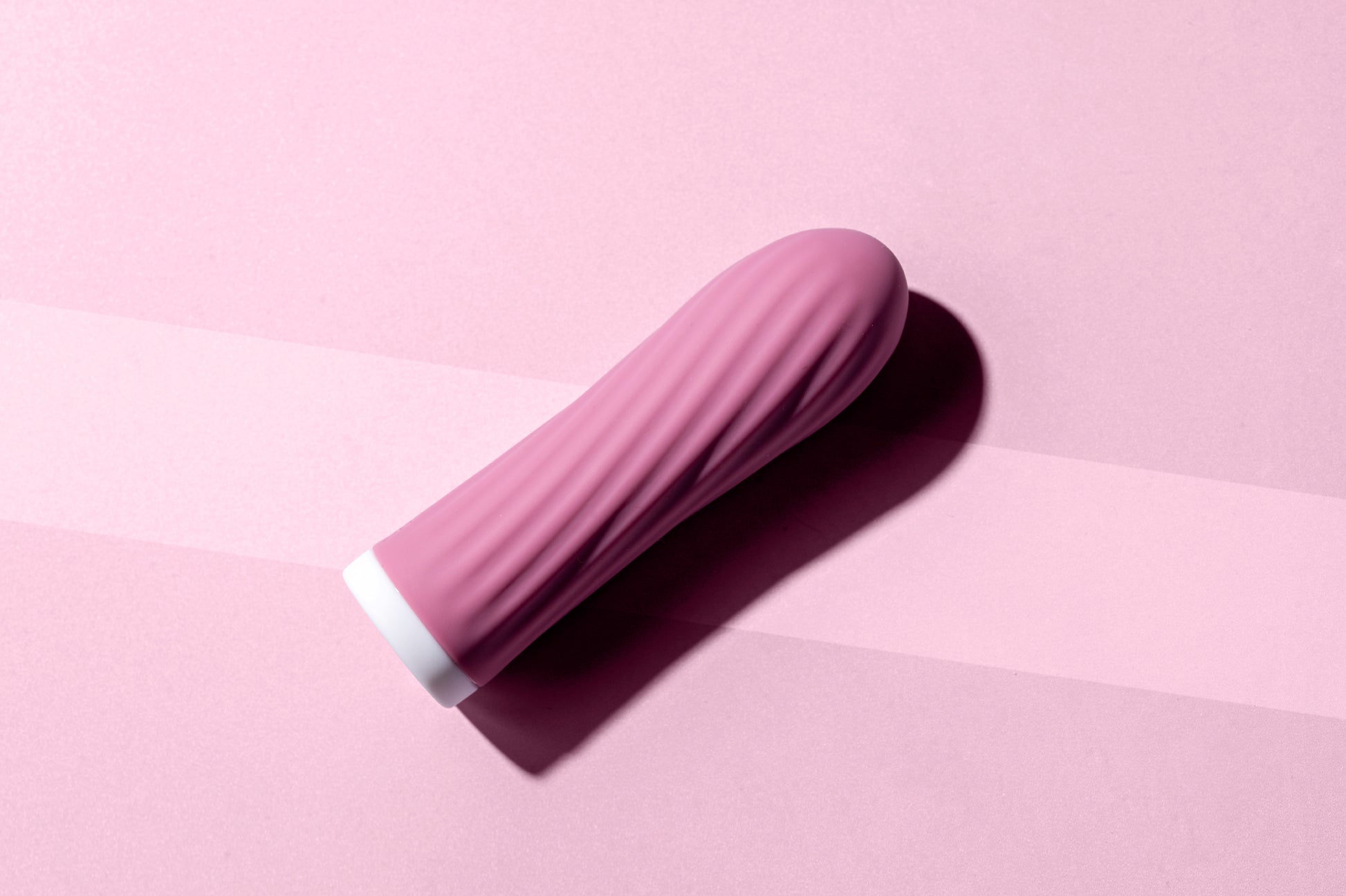 Pink bullet vibrator laying flat on pink background