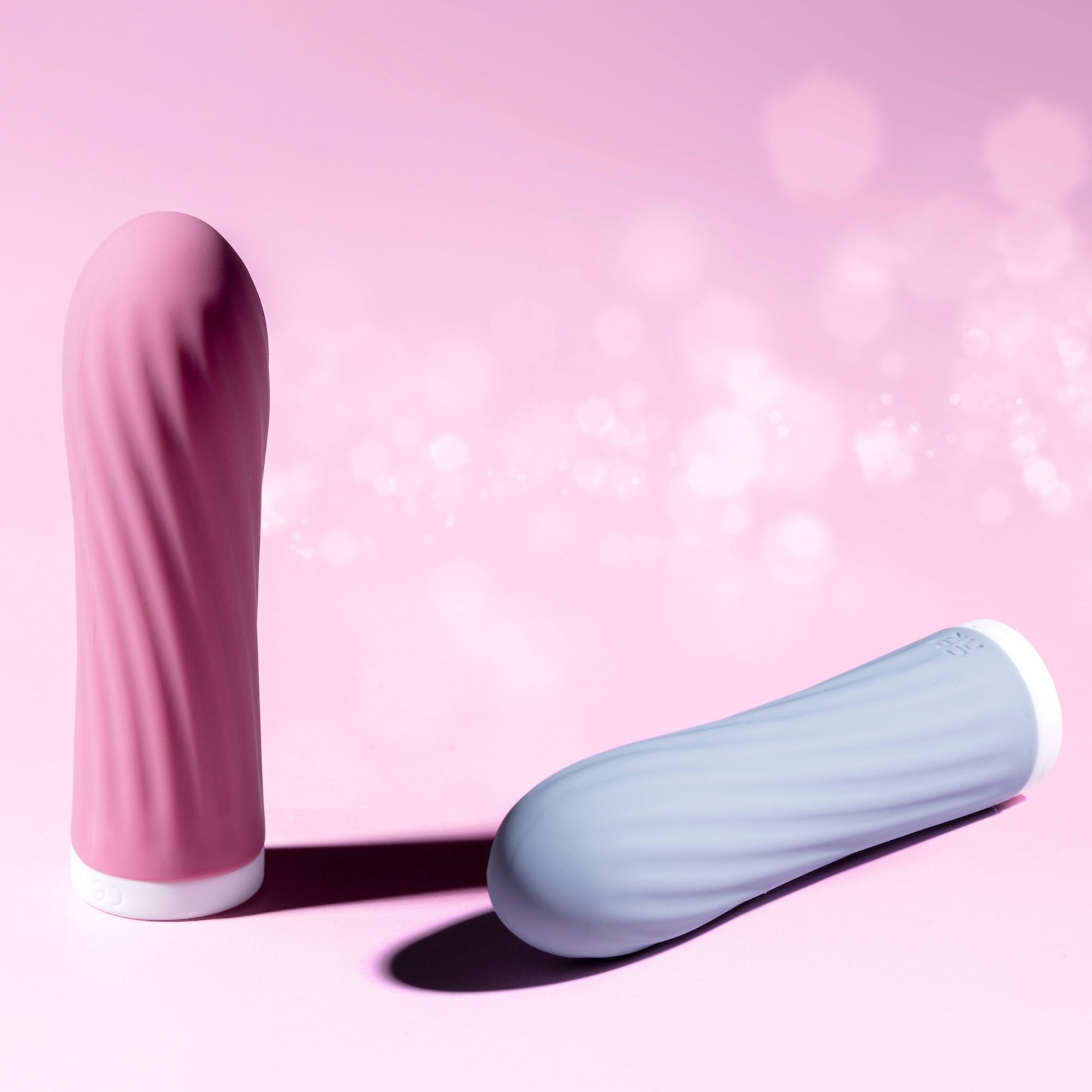 Pink and blue bullet vibrators on a pink background