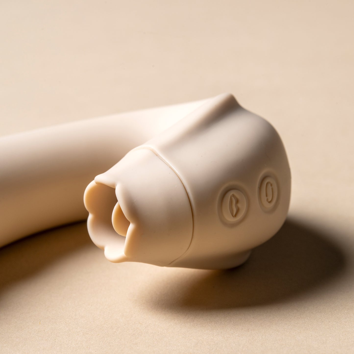 Close-up view of licking feature on vanilla clitoral vibrator, cream background

