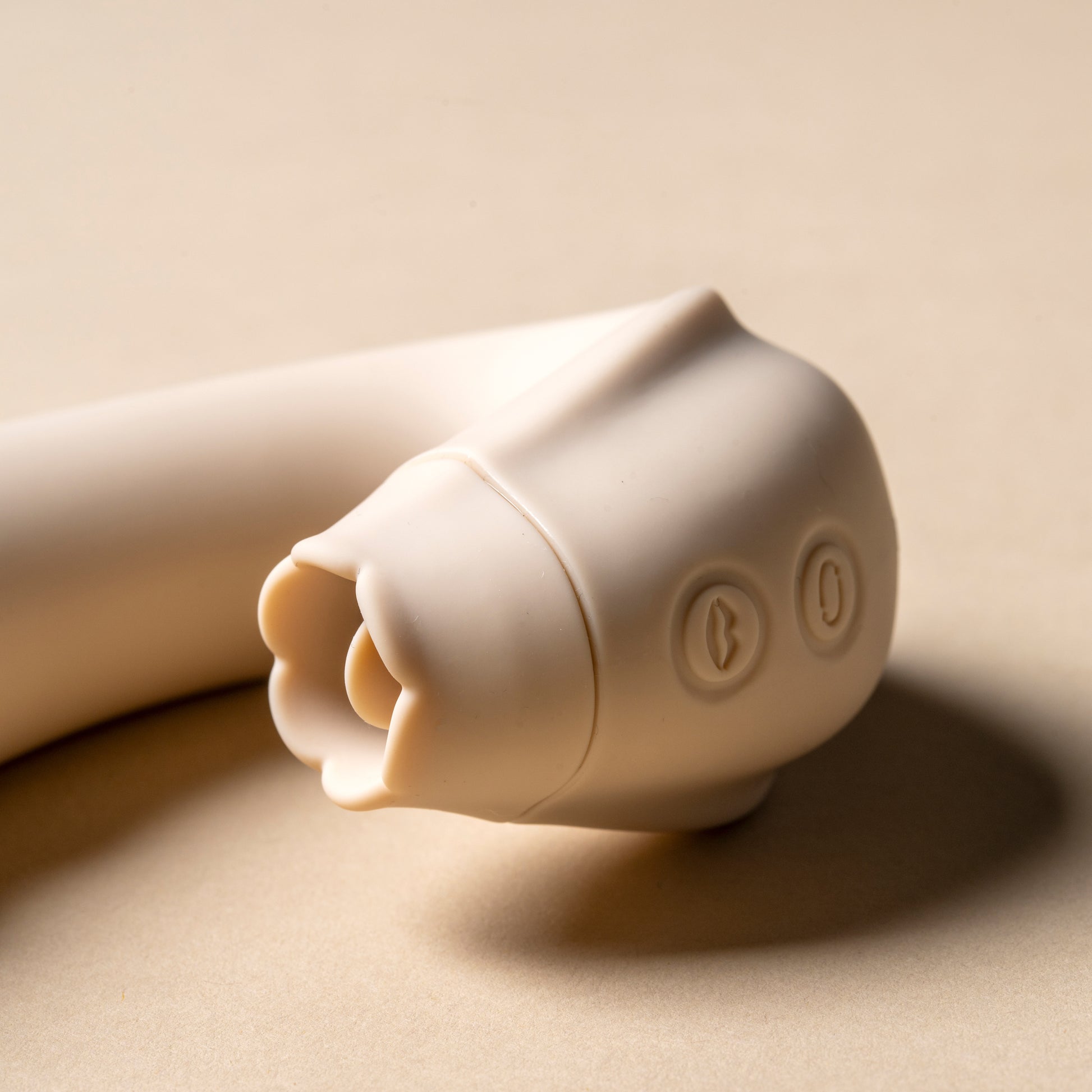 Close-up view of licking feature on vanilla clitoral vibrator, cream background

