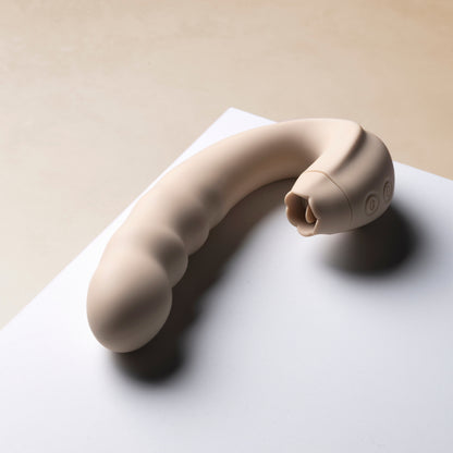 Licking vibrator on a white surface with a beige background