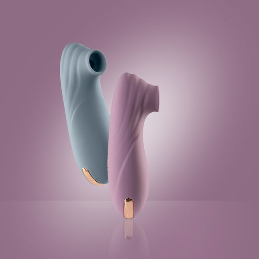 Pink clitoral suction vibrator standing on reflective surface with teal one floating, pink background

