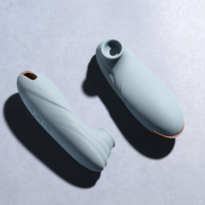 Two teal clitoral suction vibrators on a blue background