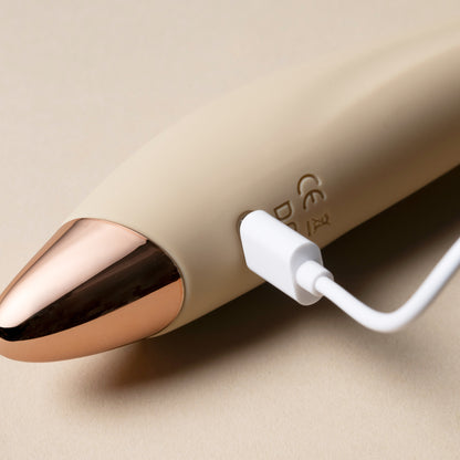 Charging cable inserted into vanilla G-spot vibrator, cream background