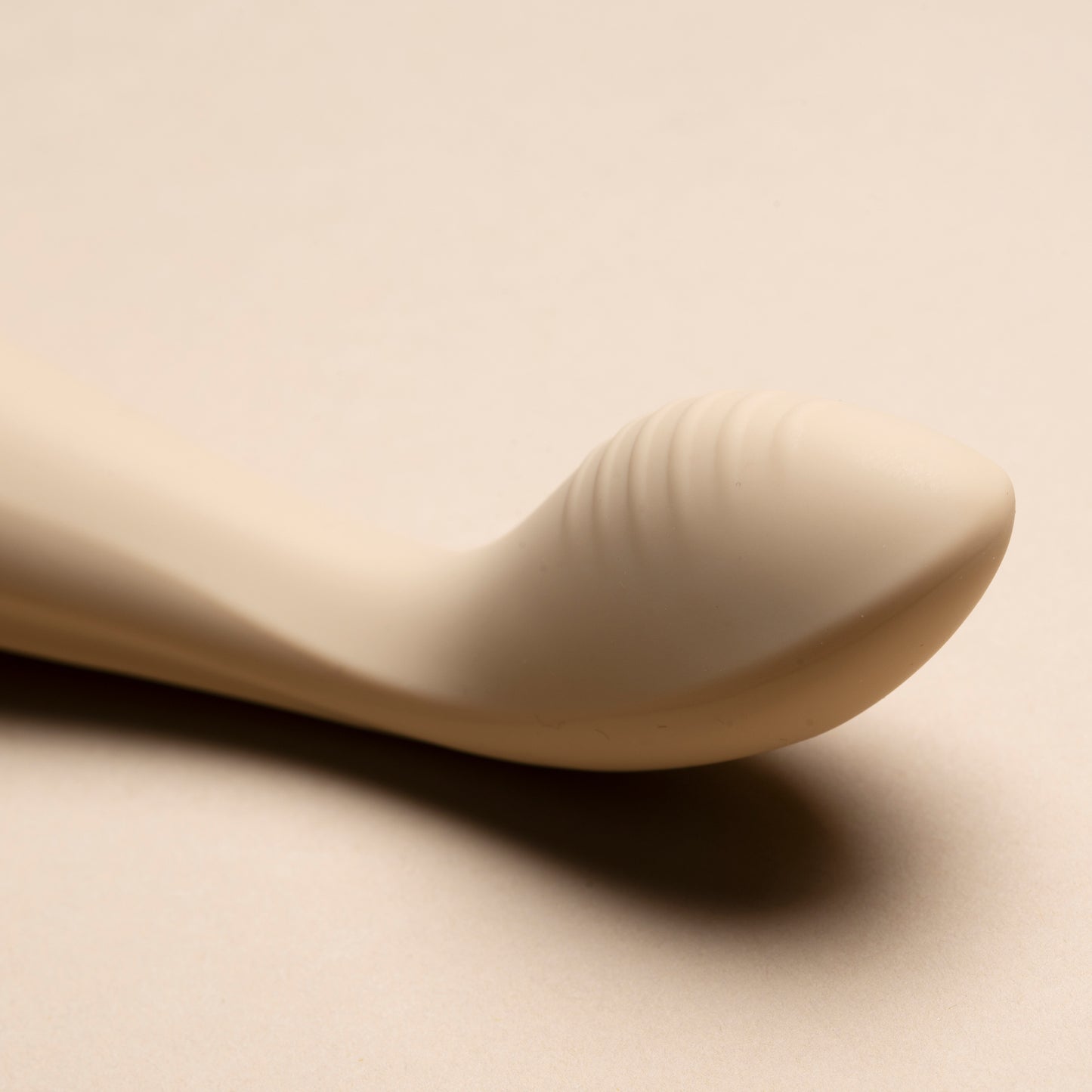 Close-up of the head of a vanilla G-spot vibrator on cream background