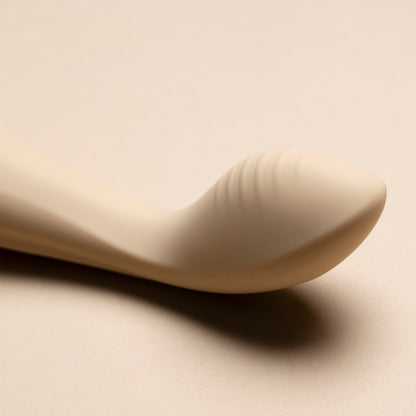 Close-up of the head of a vanilla G-spot vibrator on cream background