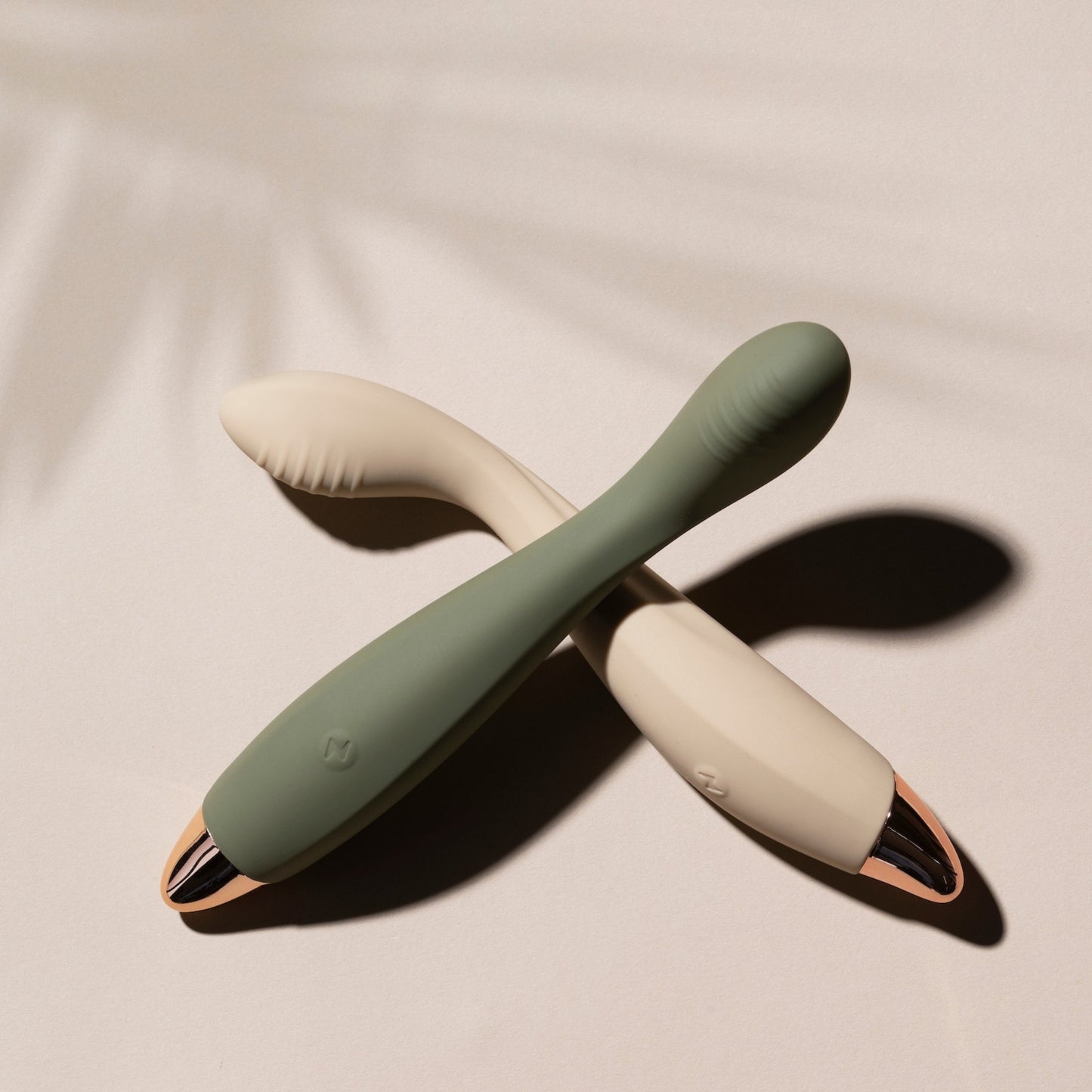 Two green and vanilla G-spot vibrators on a beige background