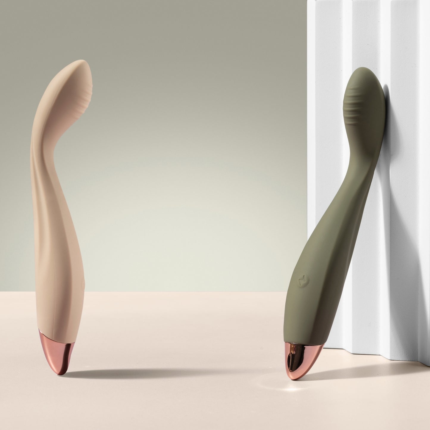 Two G-spot vibrators, one vanilla and one green, on a neutral background.