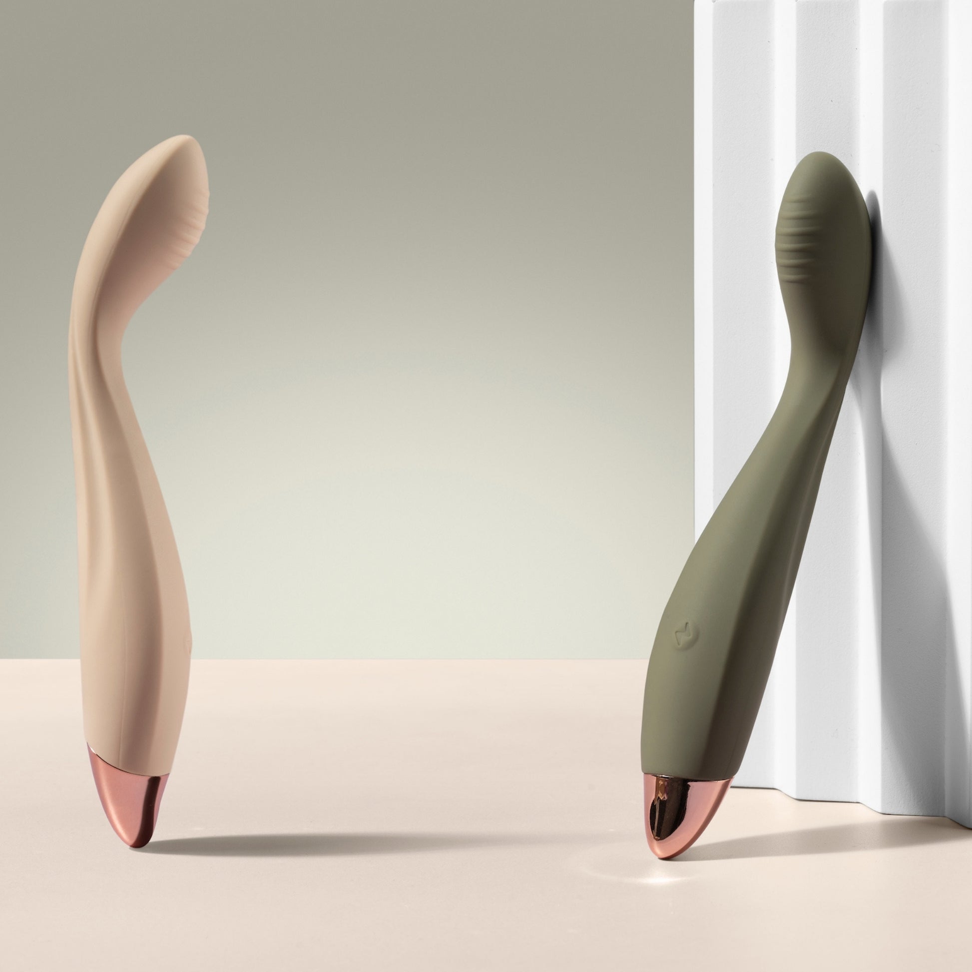 Two G-spot vibrators, one vanilla and one green, on a neutral background.
