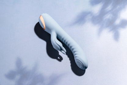 Blue rabbit vibrator laying on blue surface with soft tree shadows