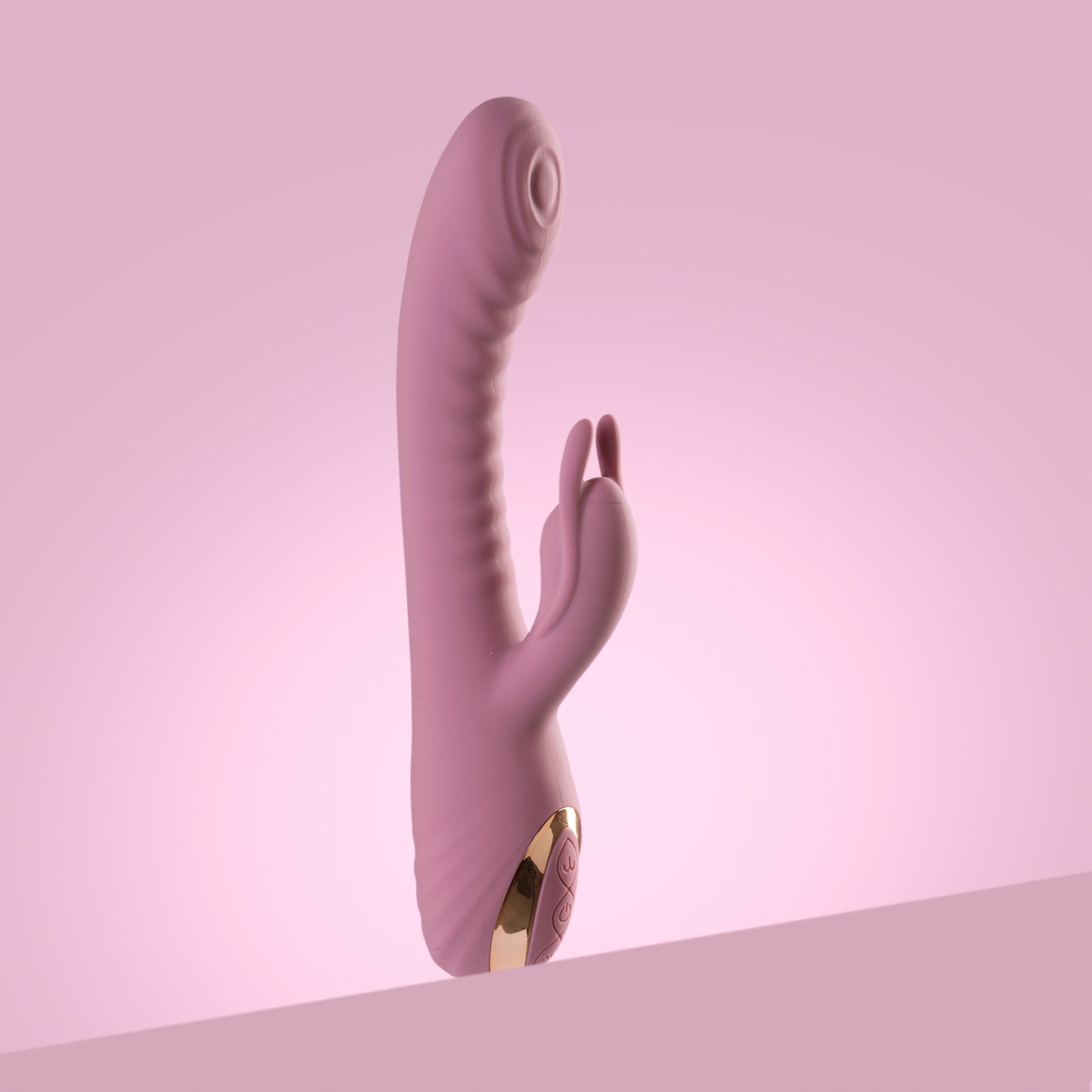 Pink rabbit vibrator standing upright on pink background

