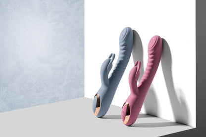Pink and blue rabbit vibrators standing upright on grey surface against white backdrop