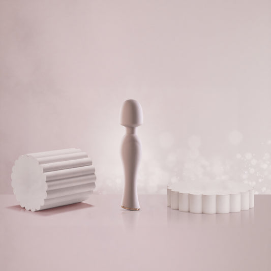 Pink wand vibrator standing on reflective pink surface with bokeh light background